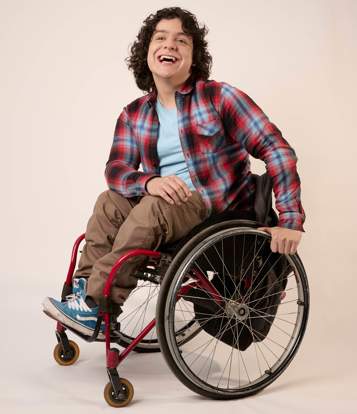 Joven en silla de ruedas sonriendo con entusiasmo, simbolizando confianza e inclusión en el talento.