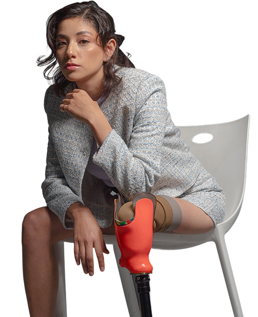 Mujer sentada con prótesis de pierna roja, representando la fuerza y elegancia de la inclusión en la moda y el trabajo.